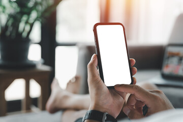 male hand holding black mobile phone with blank white screen, texting using mobile on sofa at home office. background copy space for advertise text, people contact marketing business and technology