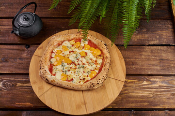 Pizza four cheeses on a wooden stand