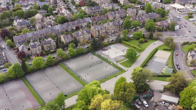 Aerial shot flying over tennis club and courts in English housing estate