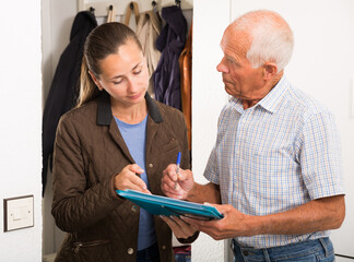 Elderly man signing financial agreement with bank worker at home