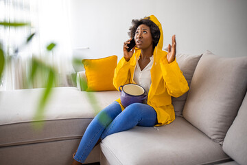 Upset household calling roof repair service while water leaking from ceiling. Upset woman with...