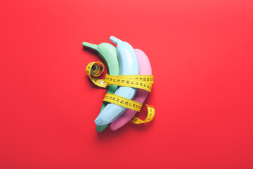 Creative composition with painted bananas and measuring tape on color background
