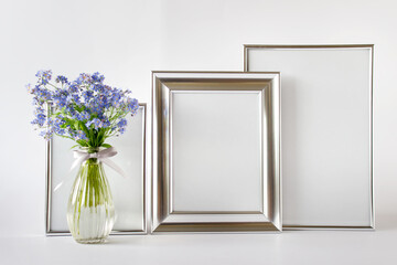 Composition with three mockup templates silver frames and blue flowers.