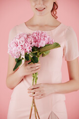 Cropped image of smiling woman holding pink hydrangea flowers