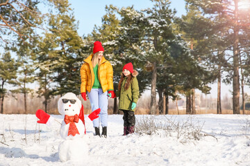 Fototapeta na wymiar Happy family with snowman in park