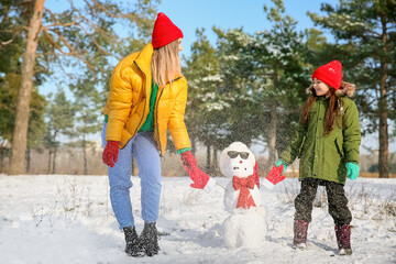 Happy family with snowman in park