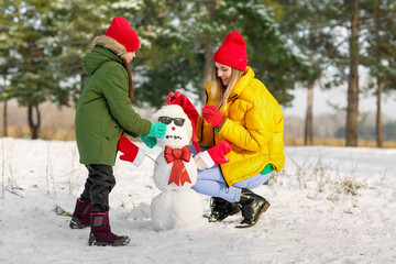 Happy family making snowman in park