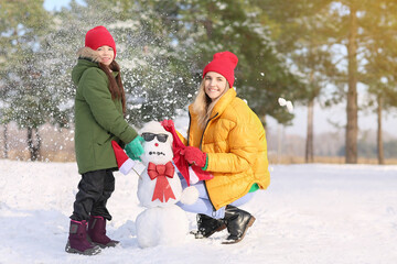 Fototapeta na wymiar Happy family making snowman in park