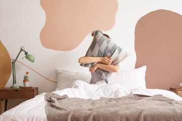 Obraz na płótnie Canvas Sleepy young woman hugging pillow in bedroom