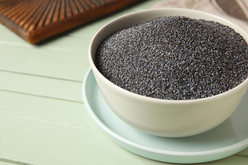 Bowl with poppy seeds on color wooden background