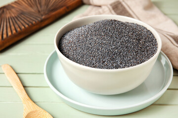 Bowl with poppy seeds on color wooden background