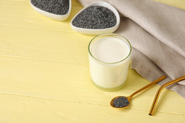 Spoon with poppy seeds and glass of milk on color wooden background
