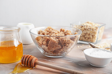 Bowl of natural scrub and ingredients on light background