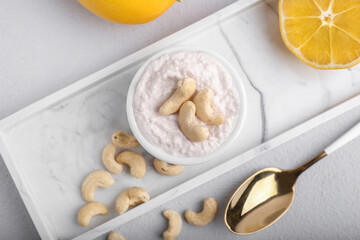 Composition with cashew sour cream, nuts and lemon on light background, closeup