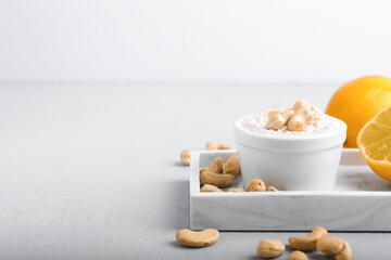 Composition with cashew sour cream, nuts and lemon on light background