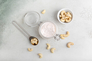 Jar with cashew sour cream and nuts on light background