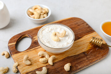 Bowl with cashew sour cream and nuts on light background