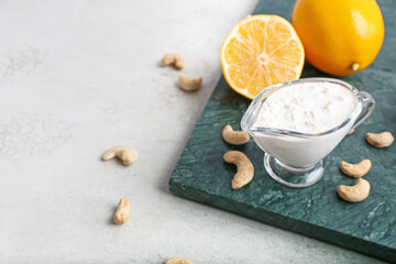 Gravy boat with cashew sour cream, nuts and lemon on light background