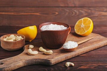 Cup with cashew sour cream, nuts and lemon on wooden background