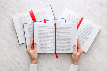 Obraz premium Woman holding open books with bookmarks on light background