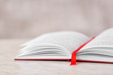 Open book with bookmark on light background, closeup