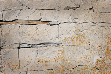 The old gray plastered wall of an industrial building with cracks and yellow biocorrosion. Grunge, retro. Texture. Space for text.