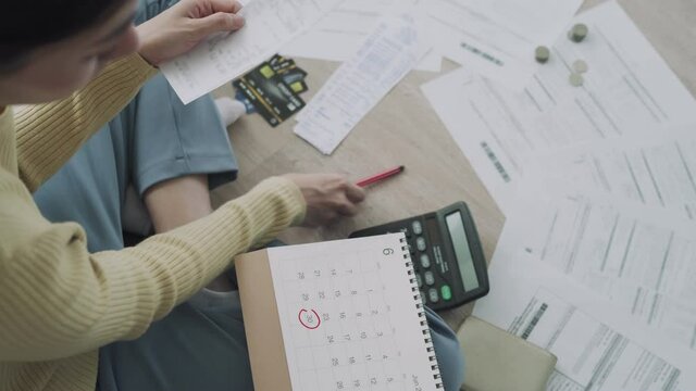 woman is reading the details of the payment date and writing the appointment date on the calendar. Women are having financial problems due to mismanagement of money. concept of money management.