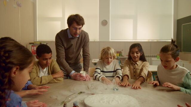 Students with teacher doing chemical experiment. Schoolteacher mixing liquids 