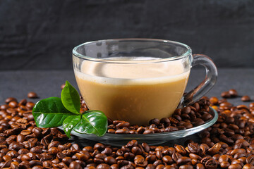 Cup of coffee on a gray table with coffee beans and coffee leaves. Closeup.