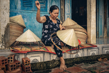 Vietnamese Old woman craftsman making the traditional vietnam hat in the old traditional house in Ap Thoi Phuoc village, Hochiminh city, Vietnam, traditional artist concept - 436594319