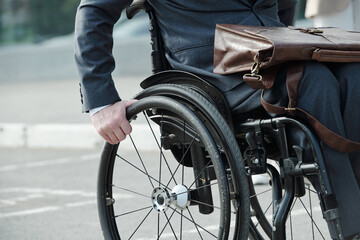 Disabled man in wheelchair moving along street for work in the morning
