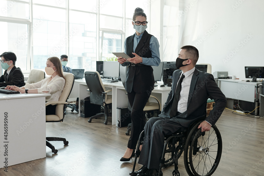 Poster two colleagues in protective masks interacting while moving along open space office