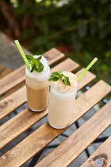 two glasses with a milkshake on a restaurant terrace on a wooden table