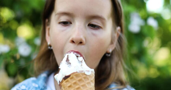Cute girl with italian ice cream cone smiling and looking at camera while resting in park on summer day, child enjoying ice cream outdoor, happy holidays, summertime