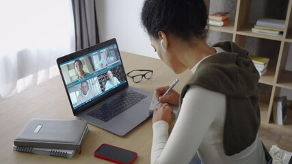 Happy African American mixed race adult student having virtual meeting with diverse people online call elearning webinar at home office talking writing notes. Video e learning conference call on pc.