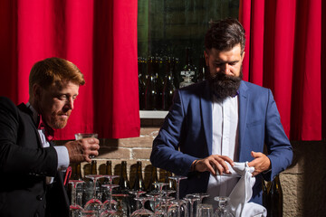 Bartender in bar. Cocktail serving. Alcoholic drink. Bartender wipes a glass.
