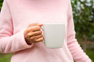 Hand woman with Sweater holding coffee white cup for drink. snack fast food in morning concept.