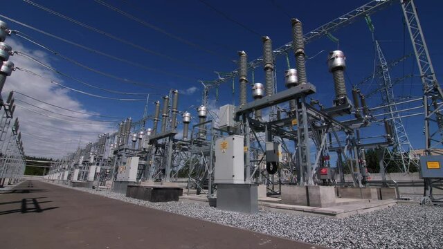 Motion along territory of large electrical distribution substation across road to powerful transformer with ceramic insulators
