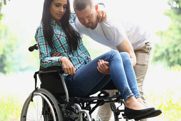Fototapeta na wymiar Man picks up disabled woman from wheelchair