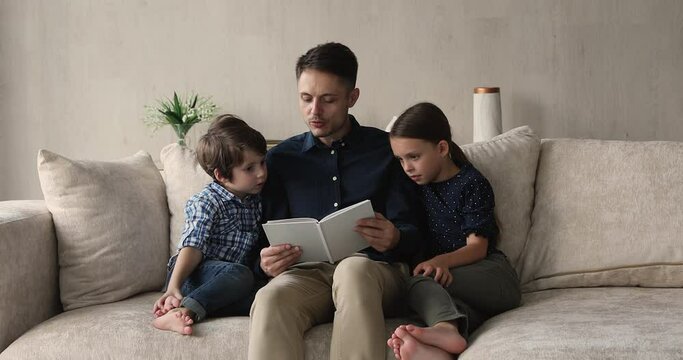 Loving father reading interesting fairytale to little son and daughter, family enjoy hobby at home. Concept of good life habit, story telling, book from library, bestseller for children and education