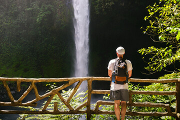 Tourist looking at the La Fortuna Waterfall in Costa Rica - obrazy, fototapety, plakaty