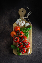 Cherry tomatoes with basil Leaves on dark stone background. Healthy nutrition organic food concept
