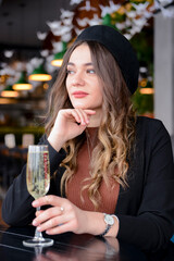 Attractive young woman with a drink in restaurant. Caucasian woman sitting in restaurant and drinking champagne.