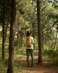Back view of woman with backpack and hat walking in forest