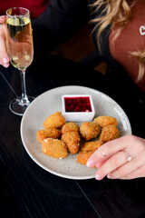 Deep fried mozarella cheese balls served on a white plate with sauce. Caucasian woman sitting in restaurant