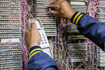 Technician checks and repairs the telephone line in PBX cabinet