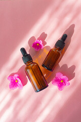 Cosmetic oil and a flower on a pink background . Cosmetic procedures. Healthy skin. Skin care. Pink...
