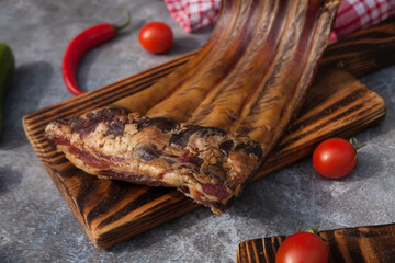 Pork ribs with spices, tomatoes and herbs on a wooden background. Smoked ribs. 