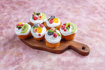 Homemade cupcakes with whipped cream and berries on top.