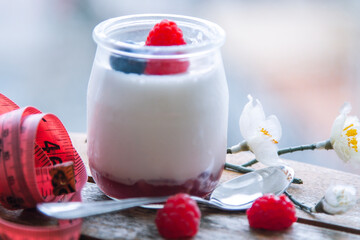 yogurt and measuring tape, diet and eating concept